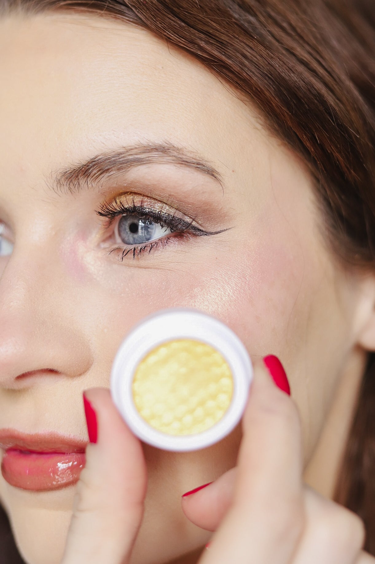 Close-up of a gold EpiLynx gluten-free vegan eyeshadow shade worn on the eye, loose pigment pot in hand