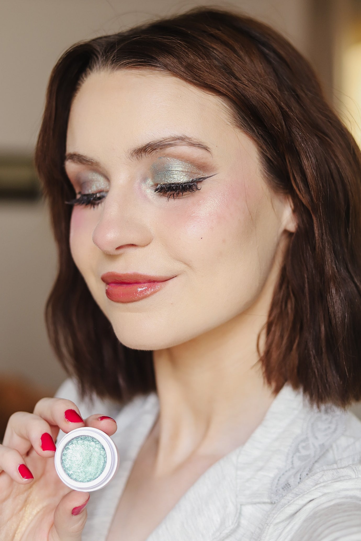 Model wearing a teal EpiLynx gluten-free vegan eyeshadow shade and holding the pigment pot