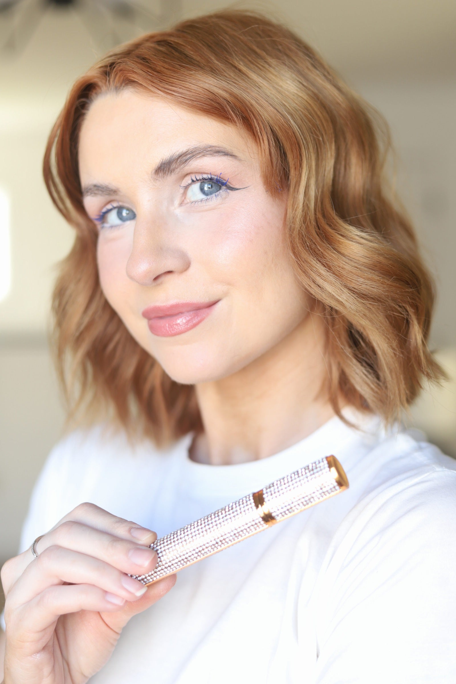 Model holding the closed EpiLynx gluten-free vegan black and blue mascara