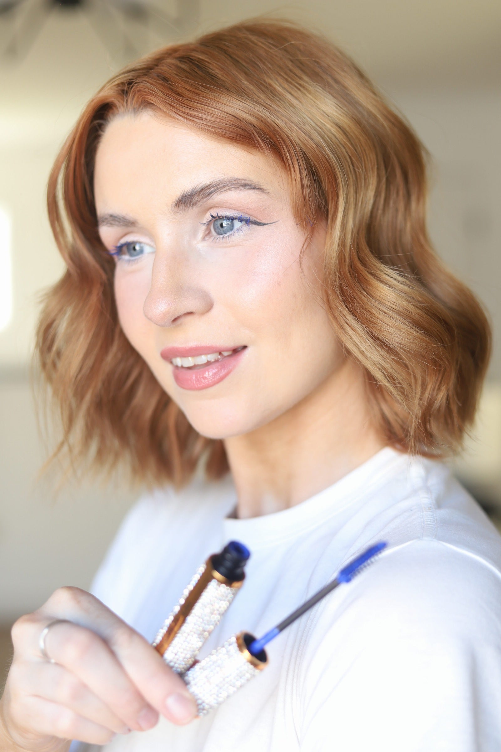 Model wearing EpiLynx blue mascara and holding the crystal-embellished tube
