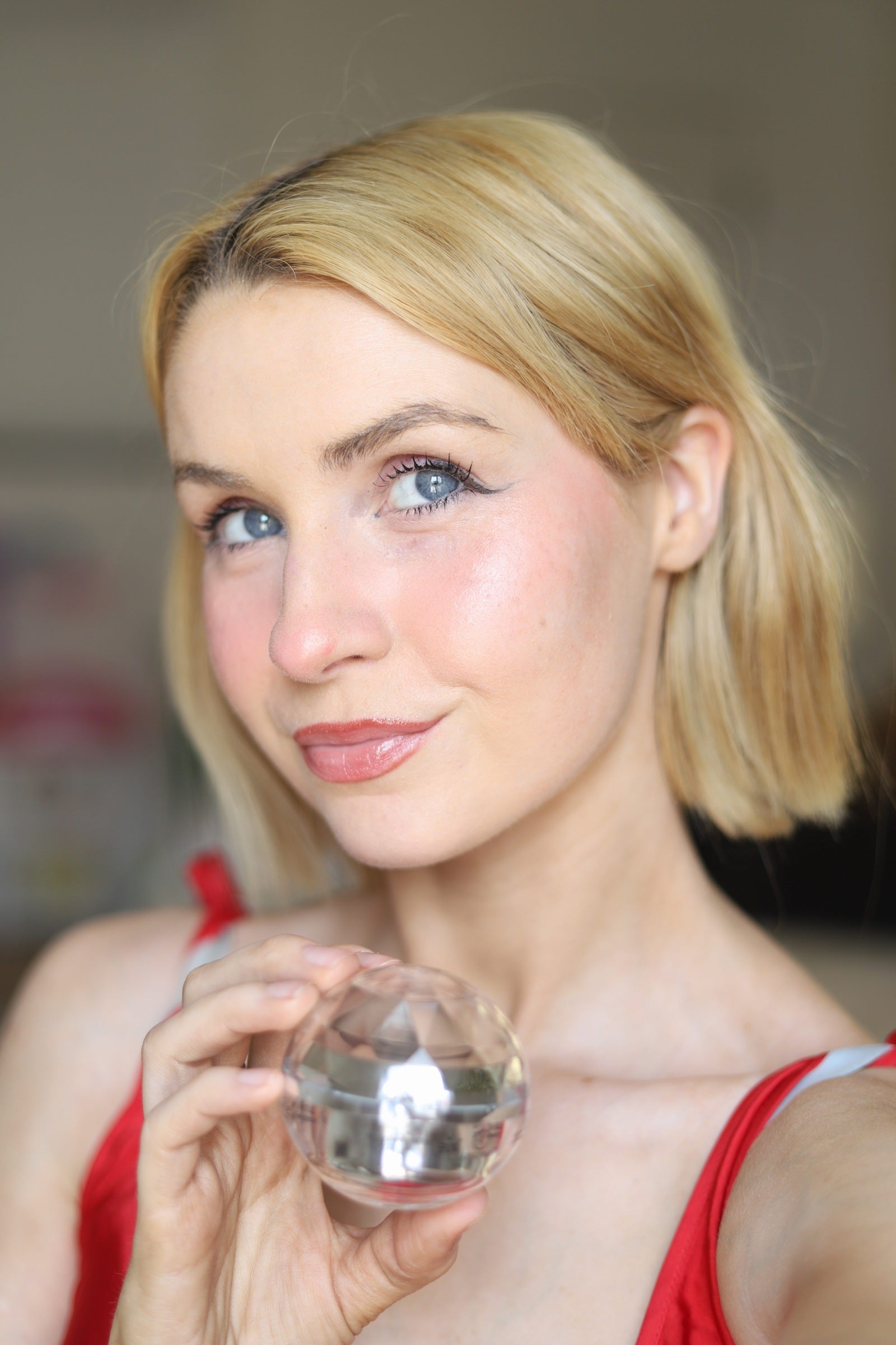 The faceted crystal jar of EpiLynx Episilk Crystal face cream held beside the face