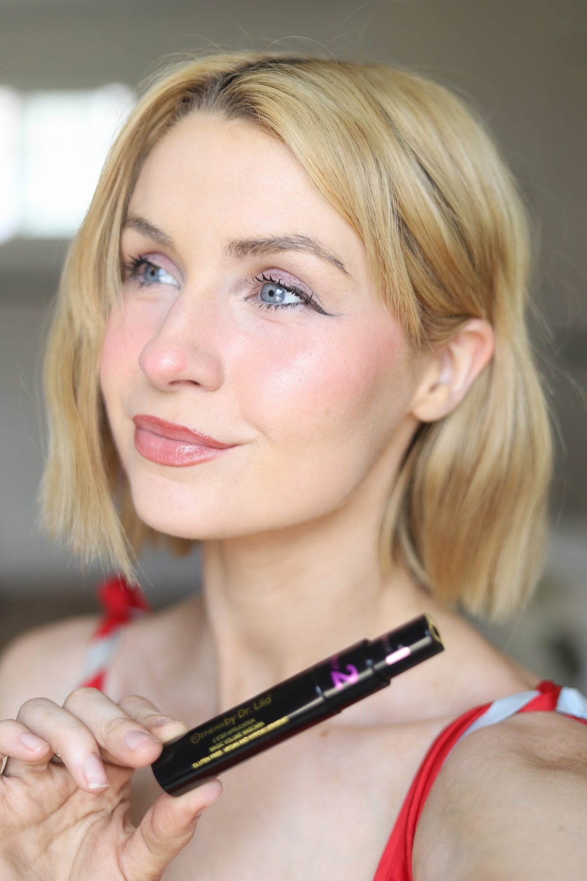 Model holding the EpiLynx gluten-free vegan 2-step volume mascara